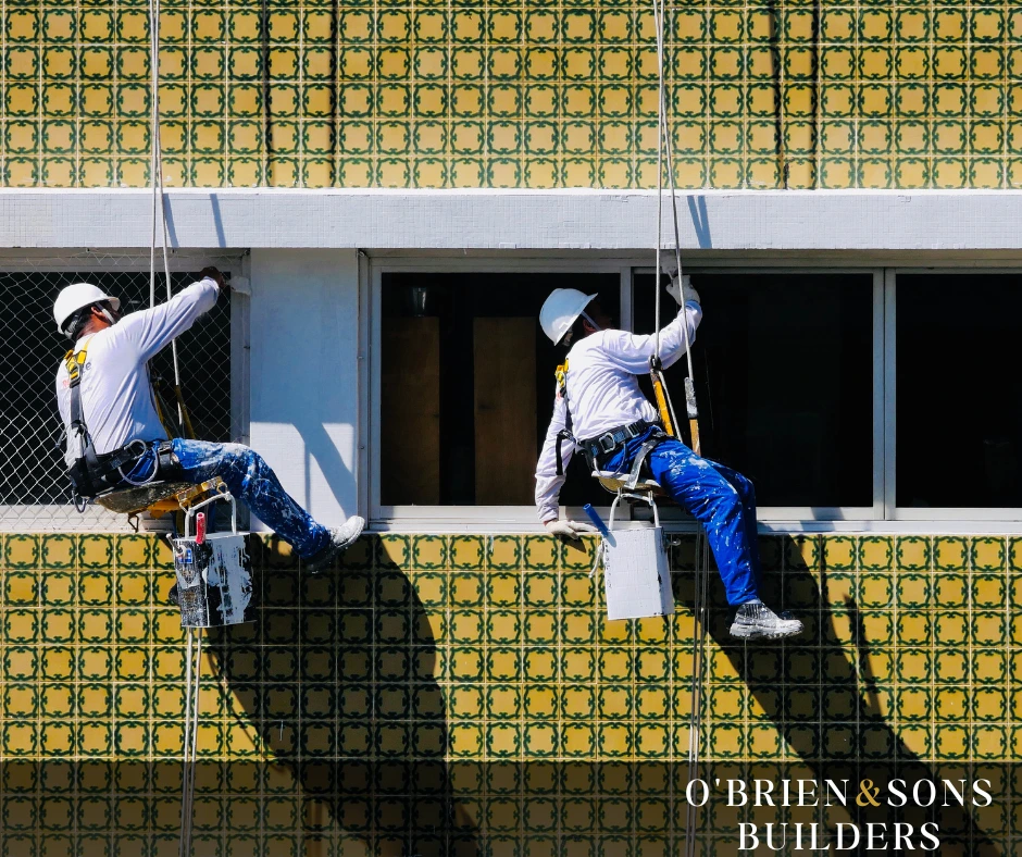 Professional painters using rope access techniques to apply exterior finishes on a tiled building façade, ensuring precision and durability in Tarzana, CA.