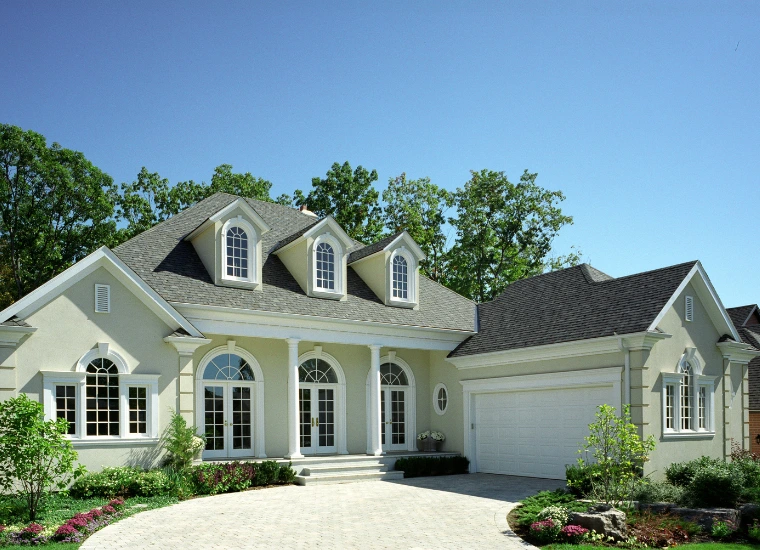 A beautifully painted light-colored house with elegant architectural details, black roof shingles, white trim, and well-maintained landscaping, showcasing enhanced curb appeal under a clear blue sky in Tarzana, CA.